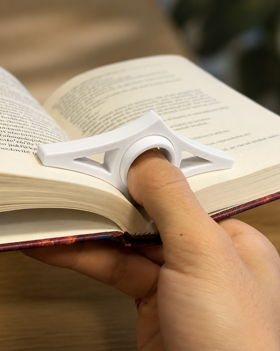 Pessoa segurando um livro aberto com uma mão usando suporte de dedo branco para leitura
