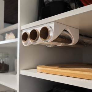 Organizador branco para três rolos instalado sob prateleira de armário de cozinha