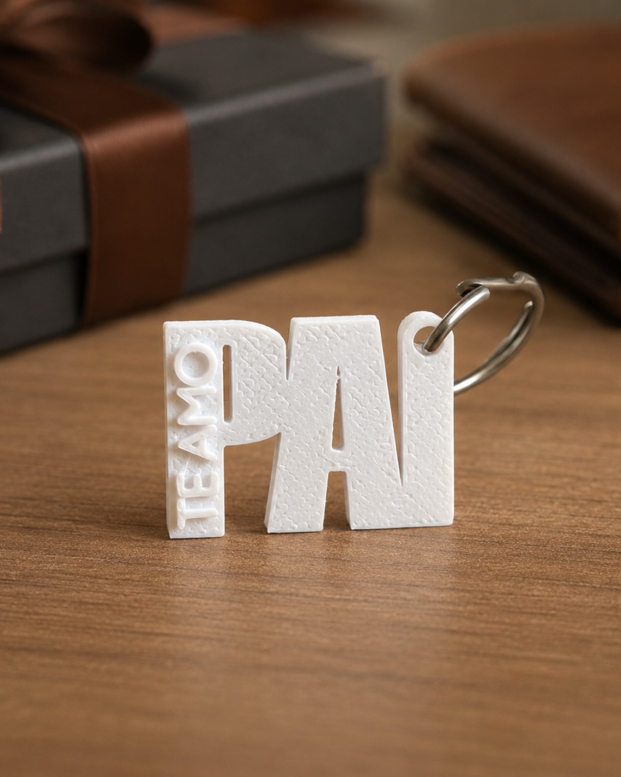Chaveiro branco personalizado Dia dos Pais com a palavra PAI e detalhe lateral TE AMO sobre mesa de madeira